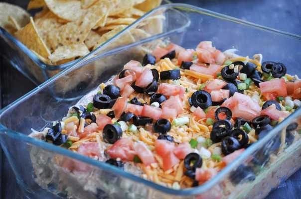 Refried beans, guacamole, sour cream/taco mix layer, cheddar cheese, green onions, tomatoes, and olives. This dip is unforgettable! 