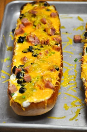 Hot open faced french bread sandwich with green chiles, ham, olives, and cheddar cheese.