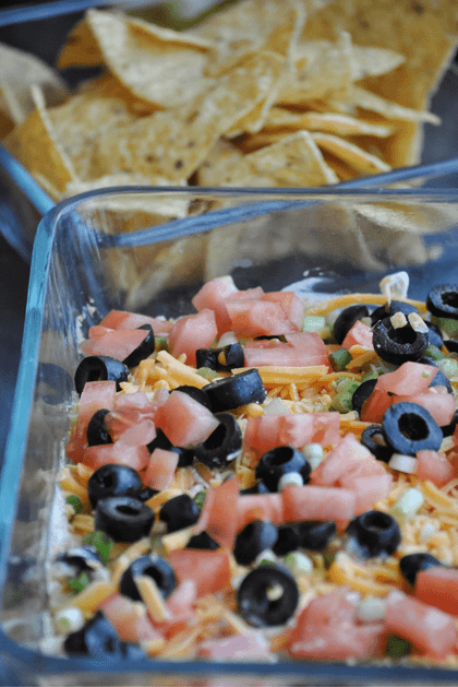 Refried beans, guacamole, sour cream/taco mix layer, cheddar cheese, green onions, tomatoes, and olives. This dip is unforgettable! 