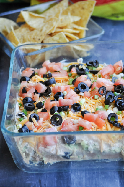 Refried beans, guacamole, sour cream/taco mix layer, cheddar cheese, green onions, tomatoes, and olives. This dip is unforgettable! 