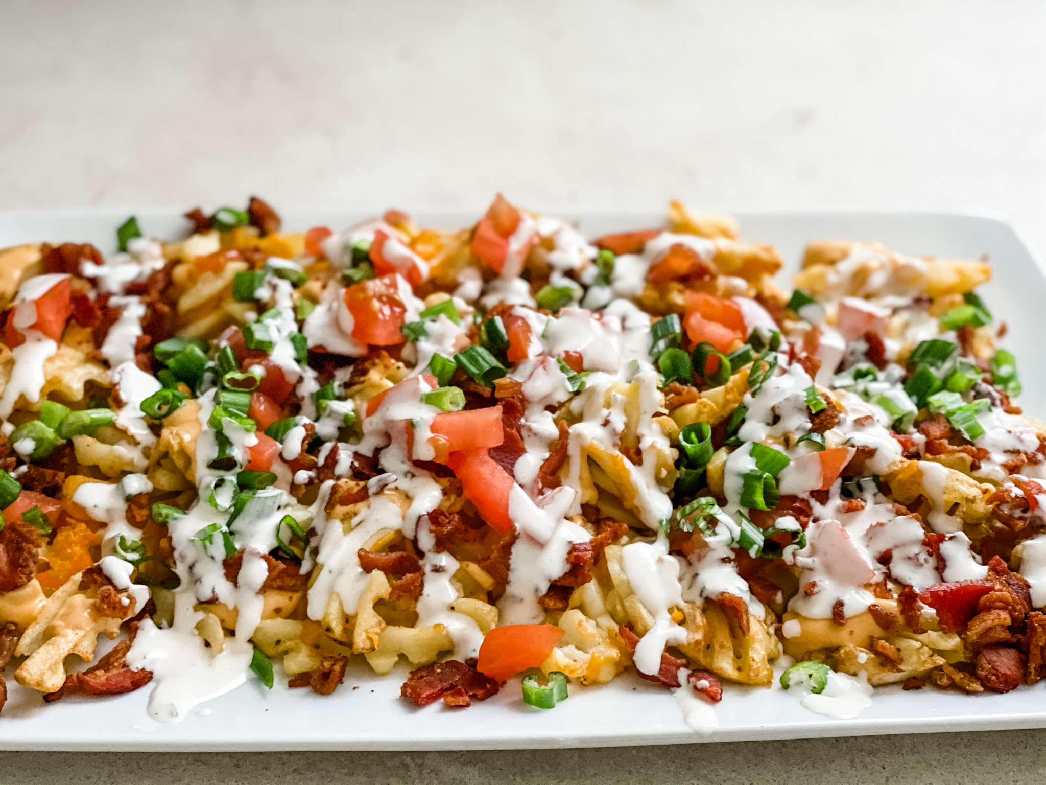 Idaho Nachos layered with crispy waffle fries, bacon, & ranch dressing.